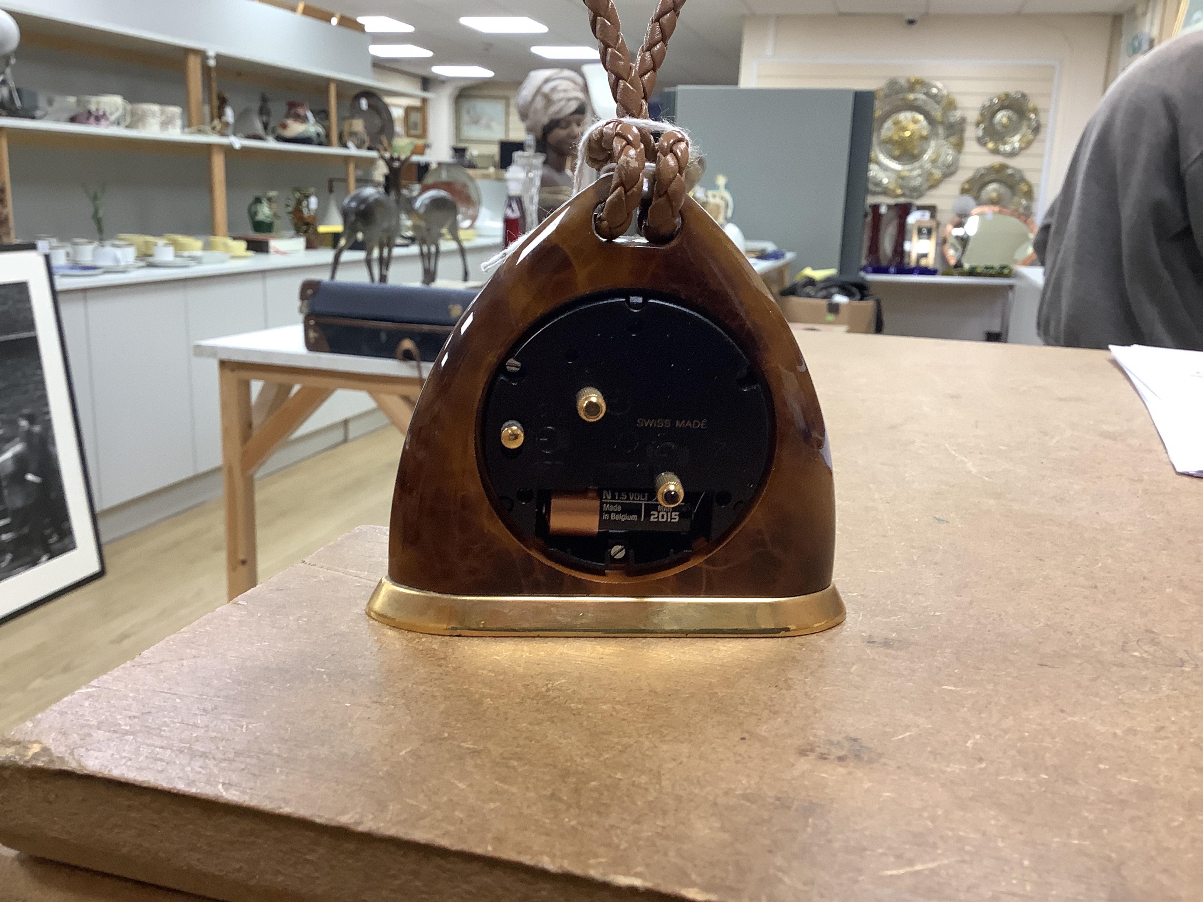 A Gucci gilt and enamelled stirrup shaped alarm clock with plaited and tasselled leather decoration, 9cm high